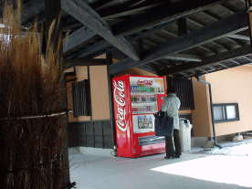 おかんがおっとんのために自販機でマロ茶を買っています。